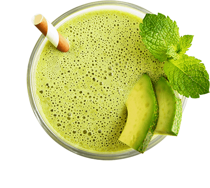 Ein grüner Smoothie, garniert mit frischer Minze und Avocado-Scheiben, gesehen von oben. Der Smoothie ist reich und schaumig mit einer hellgrünen Farbe, und ein Strohhalm steckt im Glas.